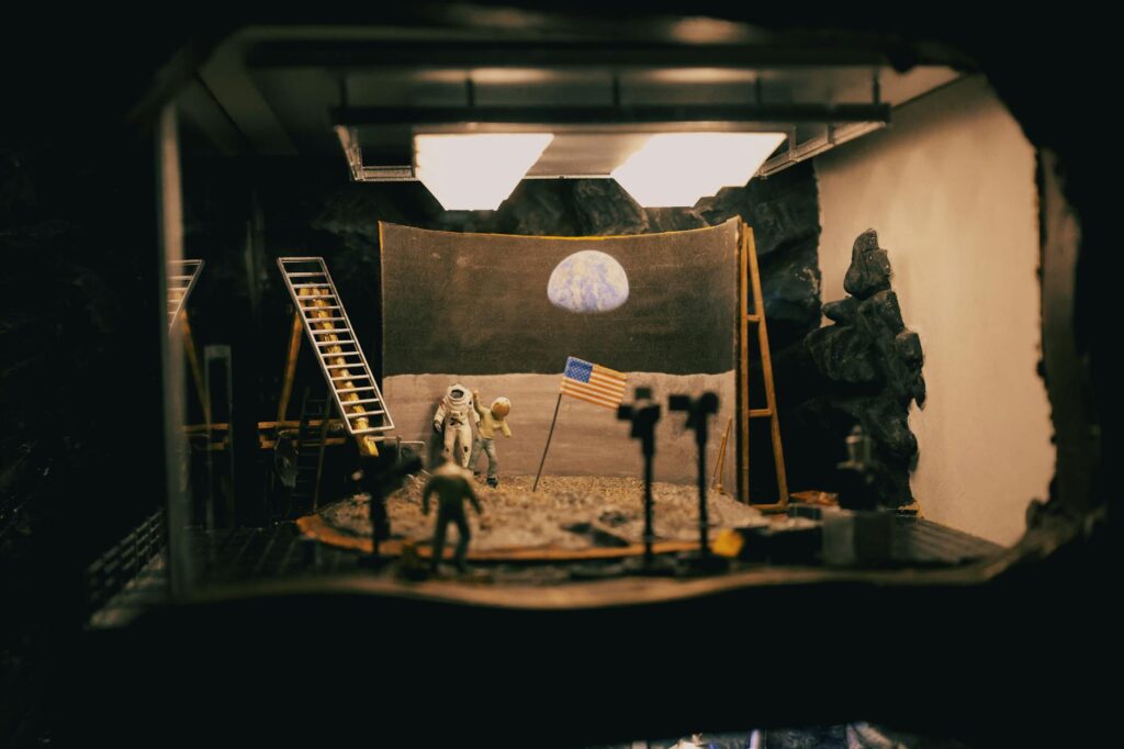 A creative diorama depicting the moon landing with astronauts and flag in a studio setup.